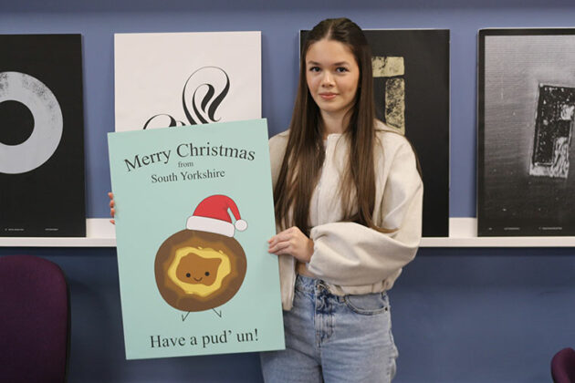 A student holding up their winning Christmas card